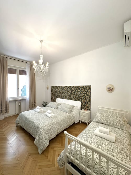 Elegante camera matrimoniale presso Il Tenore B&B a Verona con testiera decorata, lampadario di cristallo e vista sulla città