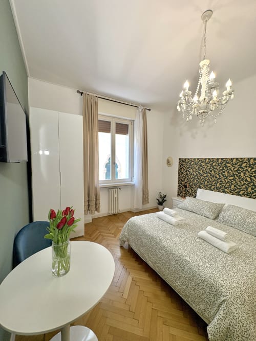 Camera elegante all'hotel Le Arche di Verona con vista sulla città, lampadario, testata ornamentale e freschi tulipani rossi