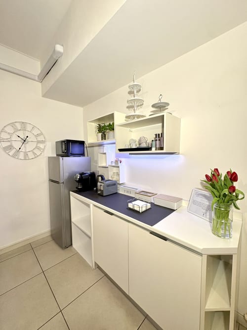 Moderna cucina del Le Arche B&B a Verona con mobili bianchi, macchina per espresso, frigorifero e tulipani rossi in vaso