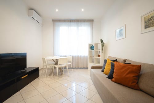 Moderno appartamento a IV House Roma con divano beige, tavolo da pranzo, TV e finestre luminose