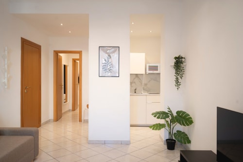 Ingresso moderno di appartamento romano con porte in legno, angolo cucina, piante in vaso e arredamento neutro presso IV House B&B