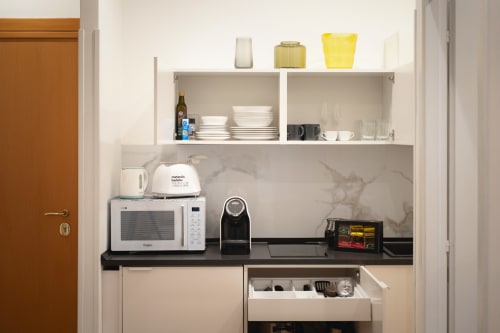 Moderna cucina attrezzata dell'appartamento IV House Roma con microonde, macchina da caffè e ripiani organizzati