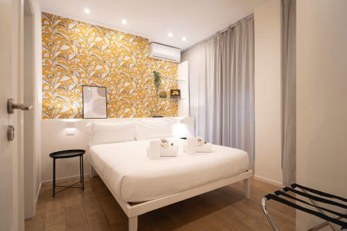 Camera da letto moderna con letto bianco, parete con motivi floreali dorati e arredamenti contemporanei presso IV House a Roma