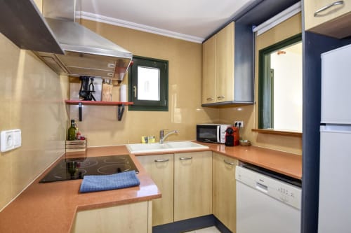 Modern kitchen in seafront apartment at Finques Garcia Enrich, Palafrugell with wooden cabinets, electric cooktop, and