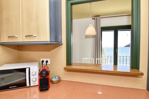 Modern kitchen with sea view in beachfront apartment, Palafrugell. Red Nespresso machine, microwave, and dining counter