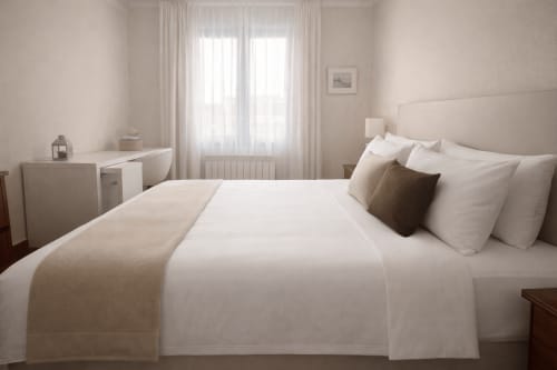 Dormitorio luminoso y minimalista en la casita Holibai de Baiona con cama de matrimonio, sábanas blancas y vistas a las montañas