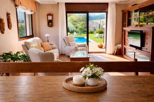 Amplia sala de estar con mesa de comedor de madera, sillones color crema, vistas a la montaña y acceso a piscina privada en la cabaña Holibai