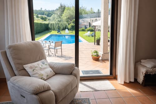 Sillón reclinable beige con suelos de terracota con vistas a piscina privada, jardín y montañas en la casa Holibai de Baiona