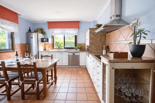Cocina de cabaña moderna en Baiona con paredes azules, gabinetes blancos, encimeras de granito, mesa de comedor y acero inoxidable