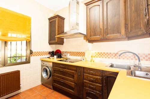 Bright kitchen at Finca Navalpino B&B in Guadamur with yellow countertops, wooden cabinets, and terracotta floor.