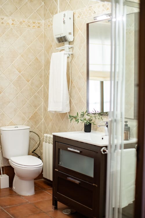Modern bathroom at Finca Navalpino B&B in Guadamur with dark vanity, white toilet, and beige tiled walls