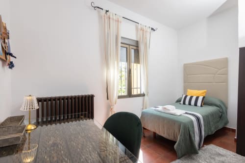 Bright bedroom at Finca Navalpino B&B in Guadamur with bed, desk, radiator, and window overlooking countryside