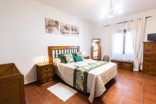 Spacious bedroom at Finca Navalpino B&B in Guadamur with wooden furniture, terracotta floors, and green accents