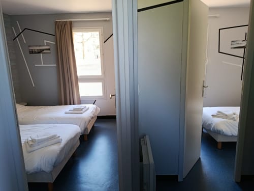 Triple bedroom at Résidence hôtelière Coiroux in Aubazine with two single beds, dark flooring, and modern furnishings.
