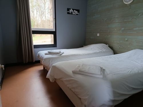 Triple bedroom at Résidence Coiroux in Aubazine with two beds, wooden accent wall, and garden views