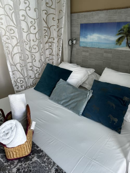 Chambre d'hôtel moderne à l'Hôtel le Soleil Couchant à St Pierre avec literie blanche, oreillers bleu marine et décor artistique tropical