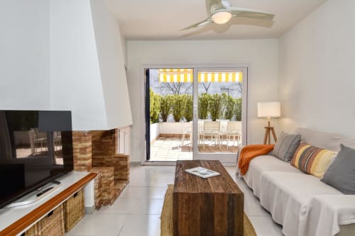 Modern beachfront apartment living room in Palafrugell with fireplace, sofa, TV, and glass doors opening to terrace with sea