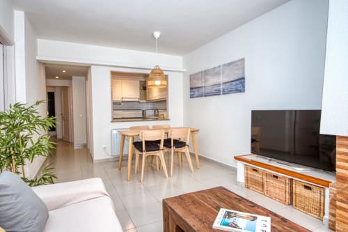 Modern beachfront apartment in Palafrugell with open-plan living, dining table, kitchen, TV, and access to Canadell beach