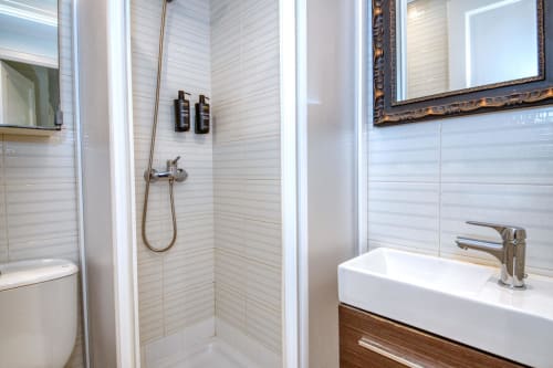 Modern bathroom with white subway tile shower, vanity sink, and bronze fixtures in beachfront apartment at Finques Garcia