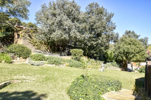 Jardins luxuriants de l'hôtel Finques Garcia Enrich à Palafrugell avec pelouse verdoyante, arbres matures et paysagisme méditerranéen