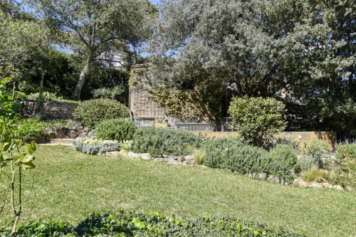 Jardin verdoyant de Finques Garcia Enrich à Palafrugell avec pelouse soignée, plantes méditerranéennes et maison en pierre