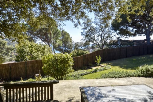 Terrasse de jardin spacieuse à Finques Garcia Enrich avec clôtures en bois, arbres matures et pelouse verdoyante à Palafrugell