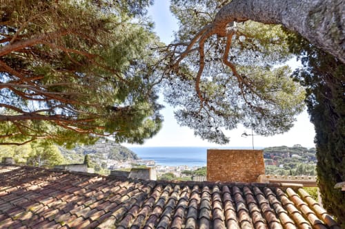 Tuiles en terre cuite encadrant la vue sur la Méditerranée depuis Finques Garcia Enrich à Palafrugell, Espagne, avec pins