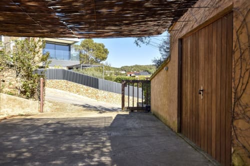 Entrée de l'allée de Finques Garcia Enrich à Palafrugell avec portail en bois et vue sur les collines