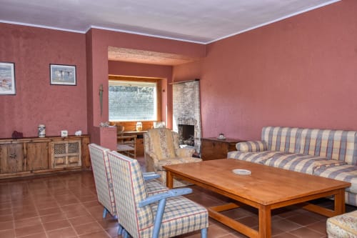 Salon spacieux de l'hôtel Finques Garcia Enrich à Palafrugell avec sièges rayés, mobilier en bois et teintes terracotta