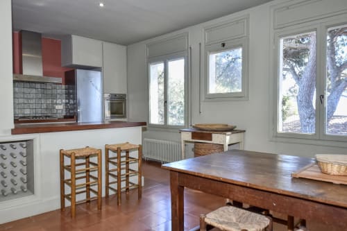 Cuisine moderne et coin repas aux Finques Garcia Enrich à Palafrugell avec table en bois, tabourets de bar et vue sur le jardin