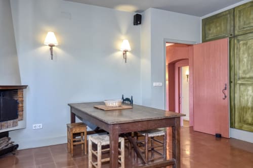 Salle à manger rustique à l'hôtel Finques Garcia Enrich à Palafrugell avec table en bois, chaises paillées, cheminée et teintes roses