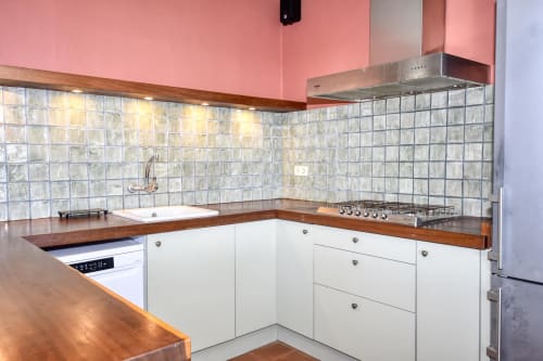 Cuisine moderne aux murs rose, armoires blanches et carrelage en verre chez Finques Garcia Enrich, Palafrugell