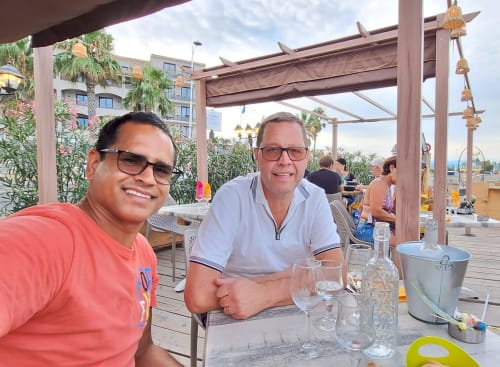 Deux hommes souriants à table en terrasse sous pergola à La Bergerie Du Moulin, Taradeau, France