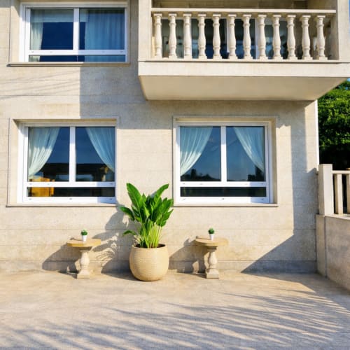 Terraza Vila Natercia en Baiona con vistas al mar, plantas en macetas y fachada moderna de villa con balcones