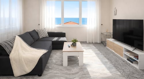 Moderno salón con sofá oscuro, vistas al mar y televisor de pantalla plana en Vila Natercia, Baiona