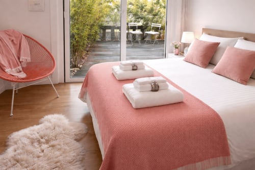 Dormitorio moderno en villa Vila Panxón cerca de Playa América, Baiona con ropa de cama rosa y blanca, vista a la terraza y diseño costero