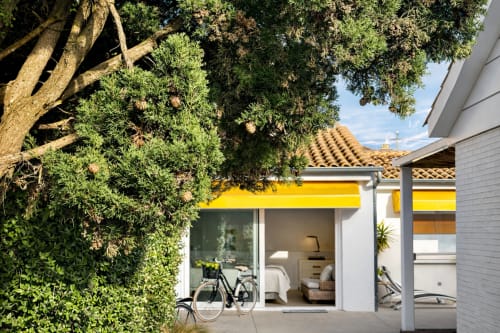 Villa moderna en Paxon con toldo amarillo, vista al mar, bicicletas y árbol maduro en primer plano