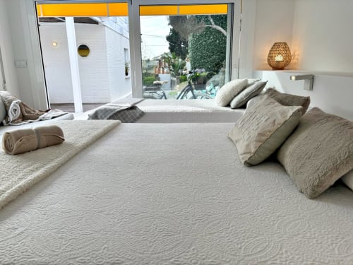 Dormitorio moderno en Vila Panxón en Paxon con camas dobles, vistas al mar a través de puertas de cristal y decoración contemporánea neutra
