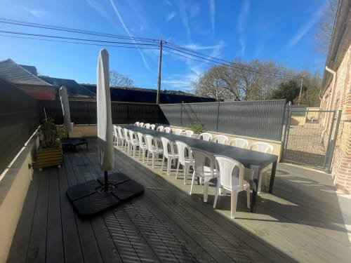 Outdoor terrace at Les Gites De Flaubert with long dining table, white chairs, and parasol in le heron