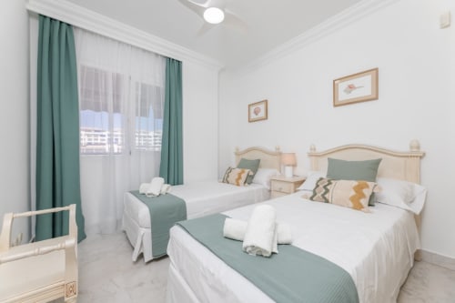 Modern twin bedroom in Marbella apartment with green accents, city views, and air conditioning