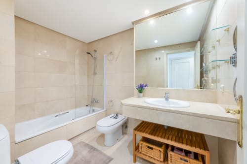 Modern bathroom in Marbella Puerto Banus apartment with beige tile, walk-in shower, white sink and vanity storage