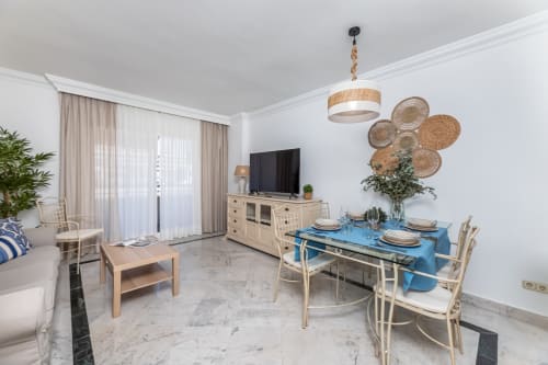 Modern Puerto Banus apartment dining area with blue table, woven wall decor, and marble flooring in Marbella