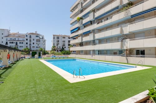 Swimming pool and green lawn at Marbella Home Rentals apartment complex in Puerto Banus, Marbella