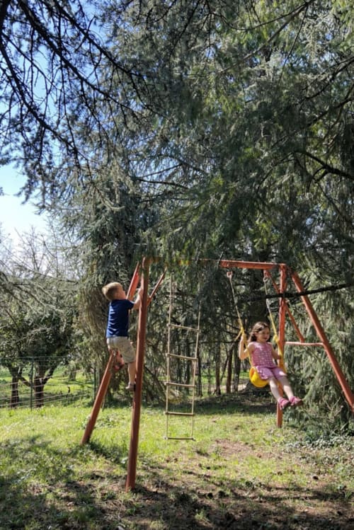 Enfants jouant sur une balançoire dans le jardin d’un gîte familial en Dordogne