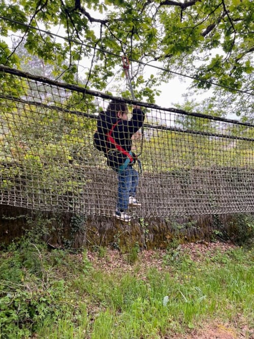 Enfant sur un parcours d’aventure en pleine nature lors d’un séjour en gîte en Dordogne