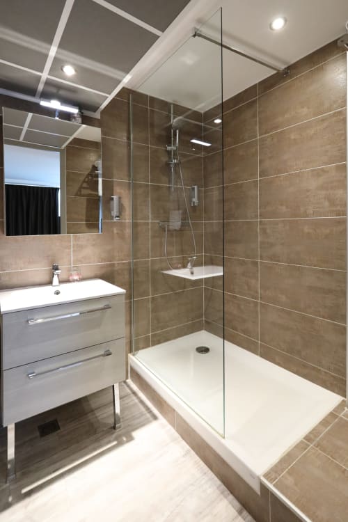 Private bathroom with walk-in shower – La Girafe Appart'Hôtel Marseille Est, stone tiles and glass panel