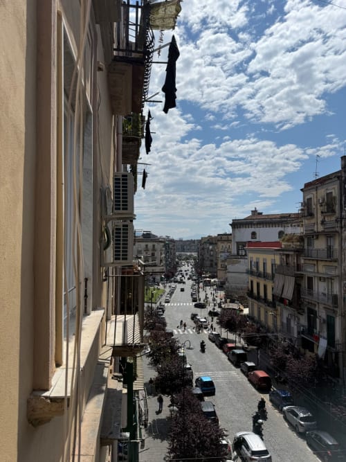 Vista della strada napoletana e degli edifici storici dal balcone di Tresette Porta Capuana con cielo azzurro
