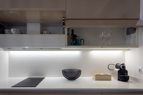 Moderna cocina de la suite The Cathedral en Unique Rooms, Burgos, con muebles blancos y luz bajo muebles