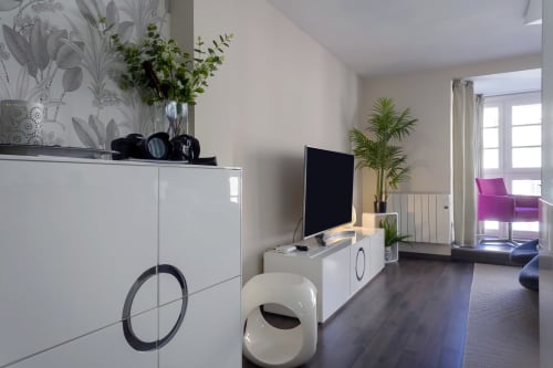 Moderna sala de estar del apartamento en The Cathedral Suite de Burgos con muebles blancos, TV, plantas en maceta y puertas al balcón