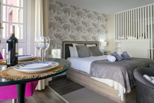 Elegante dormitorio en la Suite Catedral de Unique Rooms, Burgos, con papel pintado floral, servicio de vinos y vistas a monumentos emblemáticos
